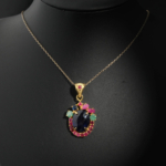 Natural faceted oval blue sapphire pendant necklace with ruby and emerald halo in gold plated 925 silver on white satin.