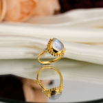 Natural teardrop blue sheen moonstone ring in vintage beaded gold plated 925 sterling silver on white satin.