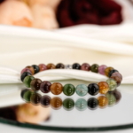 Beyaz saten kumaş ve ayna üzerinde yeşil, pembe, sarı ve siyah renkli 7A+ kalite 8 mm küre kesim doğal turmalin taşlı esnek bileklik