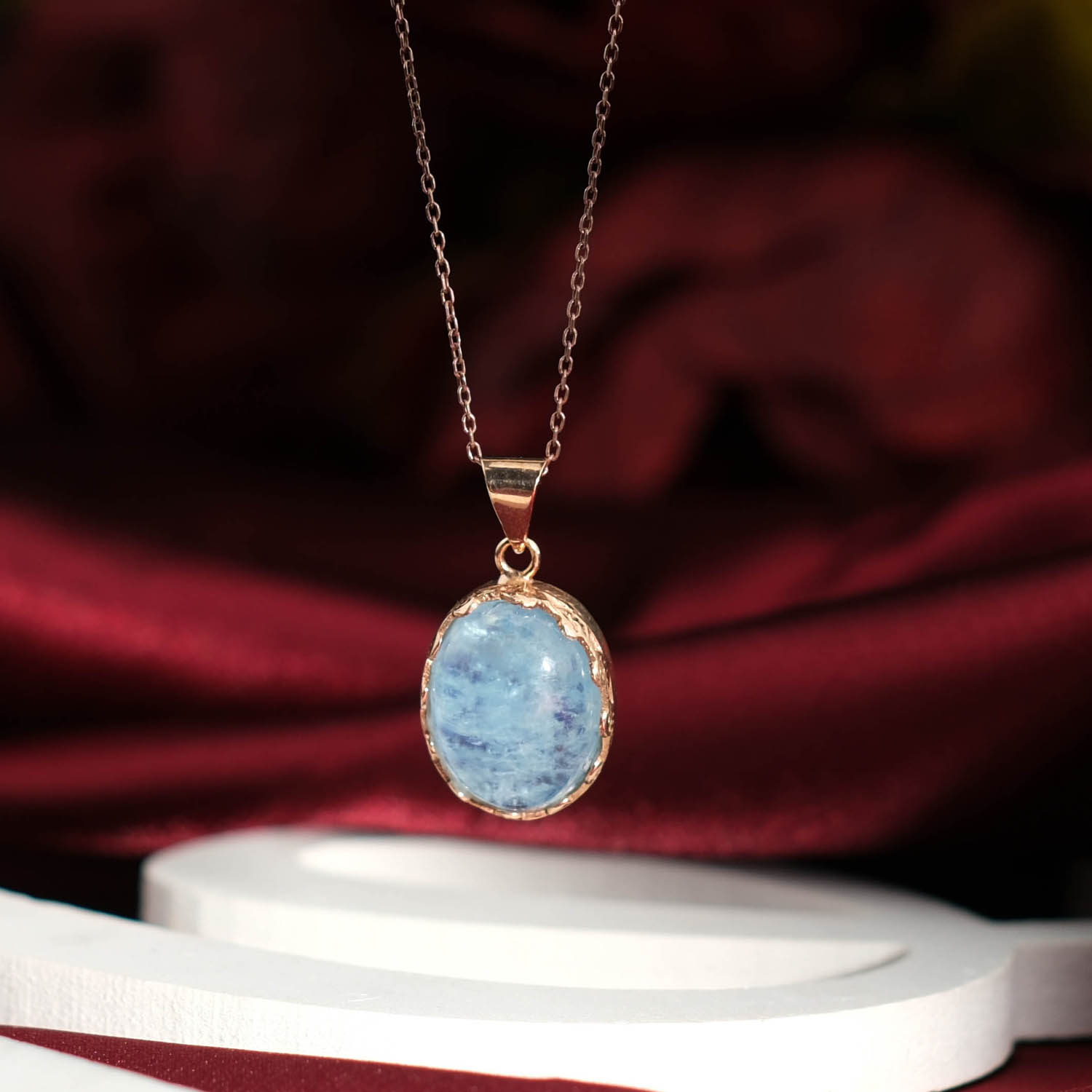 orijinal-akuamarin-dogal-tas-oval-925-ayar-gumus-rose-kolye Orijinal doğal açık mavi akuamarin taşı oval kabaşon rose altın kaplama 925 ayar gümüş tasarım kadın kolye bordo fon çekimi.