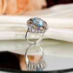 Beyaz saten kumaş ve ayna üzerinde faset oval açık mavi topaz etrafında sitrin, ametist, garnet ve zebercet taşlı saray tasarım 925 gümüş kadın yüzük.
