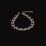 Bracciale da donna in argento 925 disegnato con pietre naturali di granato rosso a taglio ovale e dettagli scintillanti.