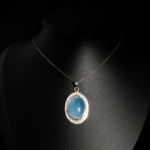 Pendentif de prestige en argent 925 orné d'une aigue-marine naturelle bleue ovale cabochon entourée de brillants oxydes de zirconium.