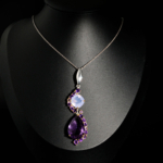 Pendentif de prestige en argent 925 orné d'une améthyste poire facettée et d'un quartz lavande sur fond noir.
