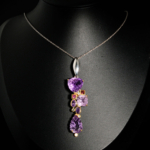 Pendentif d'exception en argent 925 orné d'une améthyste sculptée main, tourmaline rose et topazes bleues sur fond noir.
