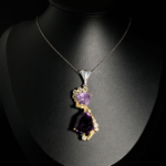 Pendentif de prestige en argent 925 orné d'une améthyste violette taille trillion et de topazes bleues sur présentoir.