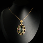 Pendentif de prestige en argent 925 orné d'une améthyste verte taillée en rose, grenat rouge et péridot sur présentoir en bois.