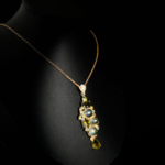 Pendentif d'exception en argent 925 orné de prehnite cabochon et péridots facettés sur fond noir.