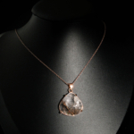 Pendentif de prestige en argent 925 plaqué or rose orné d'un quartz rutile naturel triangulaire sur fond noir.