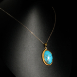 Pendentif d'exception en argent 925 plaqué or orné d'une turquoise naturelle de Nishapour sur fond noir.