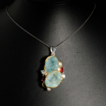 Pendentif d'exception en argent 925 orné de tranches d'aigue-marine naturelle, tourmaline rouge et topazes bleues sur fond noir.