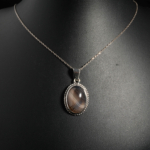 Pendentif élégant en argent 925 orné d'une agate rubanée naturelle grise et marron sur buste noir de face.