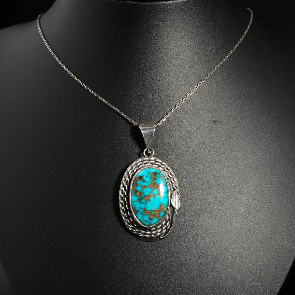 Pendentif unisexe en argent 925 orné d'une turquoise naturelle ovale avec matrice sertie d'un cadre torsadé.