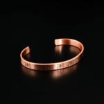 Pure solid copper adjustable cuff bracelet with engraved geometric star symbols on mirror reflection and white satin.