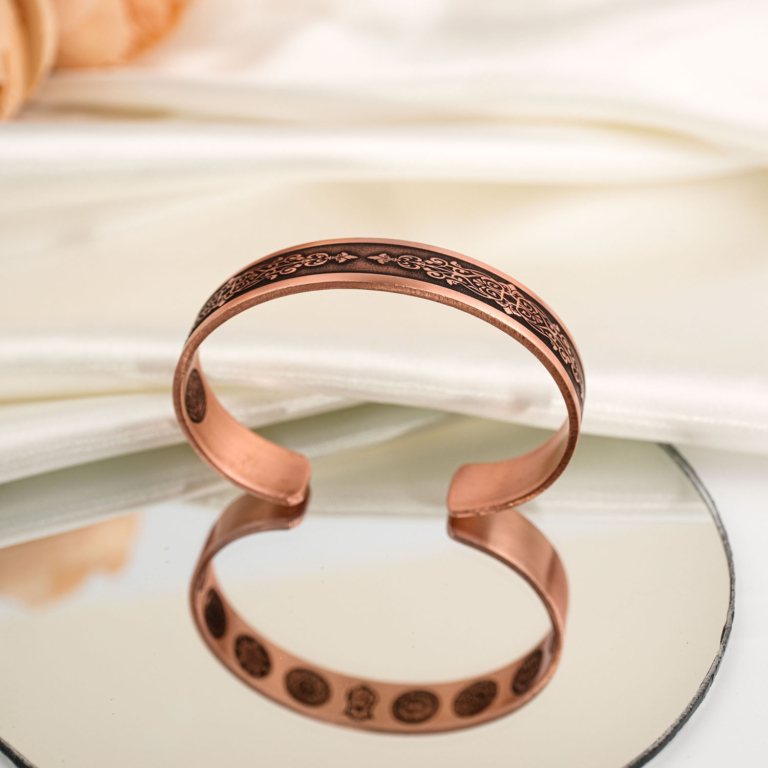 Pure solid copper adjustable cuff bracelet with engraved traditional protection symbols on mirror reflection and white satin.