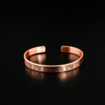 Pure solid copper adjustable cuff bracelet with engraved wave and spiral patterns on mirror reflection and white satin.