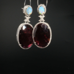 Елегантни дамски висящи обици от сребро 925 с фасетиран естествен гранат, кабошон опал и инкрустирани диаманти на черен фон.