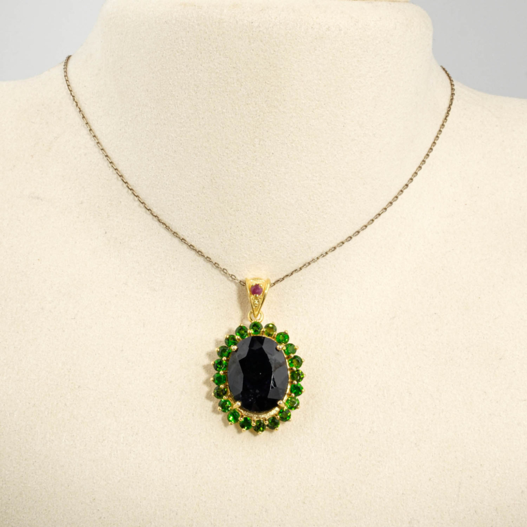 Collier médaillon royal pour femme avec saphir bleu foncé et tsavorite vert en argent 925 plaqué or sur satin blanc.
